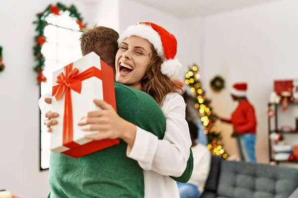 Grupa Młodych Ludzi Spotkaniu Świątecznym Para Gospodarstwa Prezent Przytulanie Domu — Zdjęcie stockowe