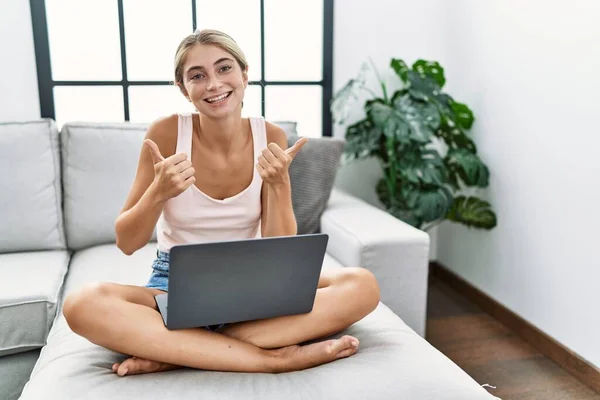 Young Blonde Woman Using Laptop Home Sitting Sofa Success Sign — Stockfoto