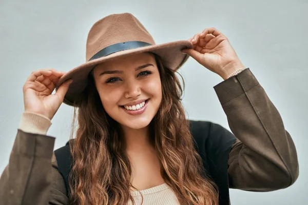 Genç İspanyol turist kadın gülümseyerek şehirde şapkasını tutarken mutlu..