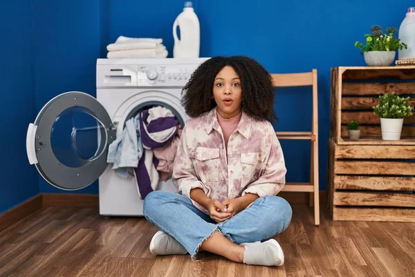 年轻的非洲裔美国女人坐在地板上洗衣服 吓得满嘴诧异 满脸诧异 — 图库照片