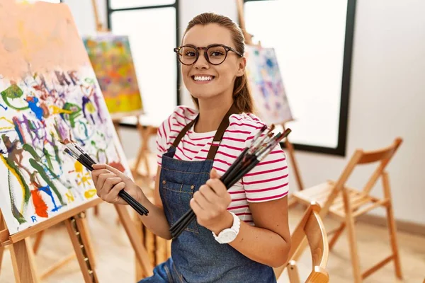 Jovem Mulher Sorrindo Confiante Segurando Pincéis Estúdio Arte — Fotografia de Stock
