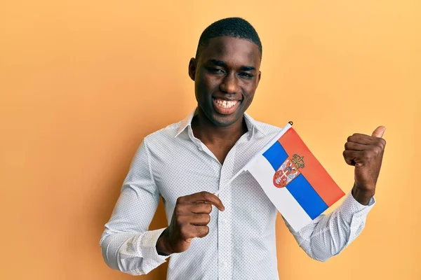 Young African American Man Holding Serbia Flag Pointing Thumb Side —  Fotos de Stock