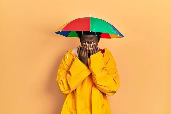 疲労感と頭痛 疲れた表情のために黄色のレインコートの摩擦目を身に着けている若いアフリカ系アメリカ人男性 ビジョンの問題 — ストック写真
