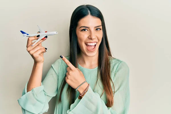 Young Hispanic Woman Holding Airplane Toy Smiling Happy Pointing Hand — ストック写真