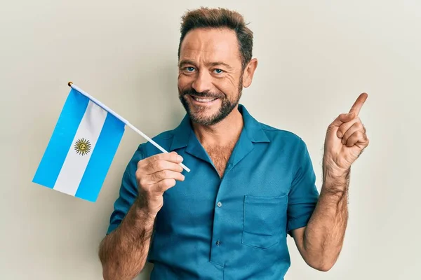Medelålders Man Håller Argentina Flaggan Ler Glad Pekar Med Hand — Stockfoto