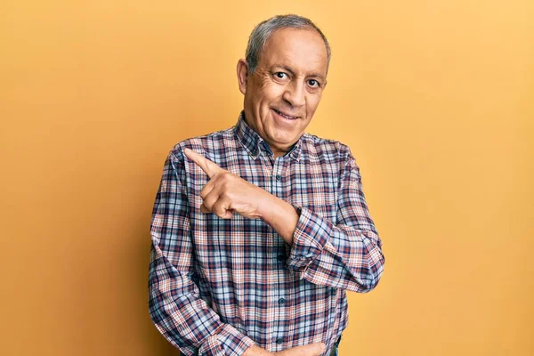 Yakışıklı, gri saçlı, rahat tişörtlü, neşeli yüzlü, elleri ve parmaklarıyla yüzünü gösteren mutlu ve doğal bir ifadeyle yakışıklı bir adam. 