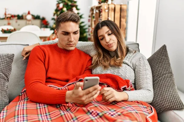 Young Hispanic Couple Sitting Sofa Christmas Thinking Attitude Sober Expression — Zdjęcie stockowe
