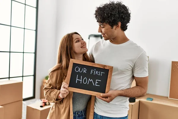 Genç çift yeni evimizdeki ilk mesajımızla birlikte mutlu bir şekilde ellerinde tahtayla gülümsüyor..