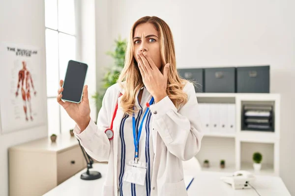 Young Blonde Doctor Woman Working Clinic Showing Smartphone Screen Covering — Photo