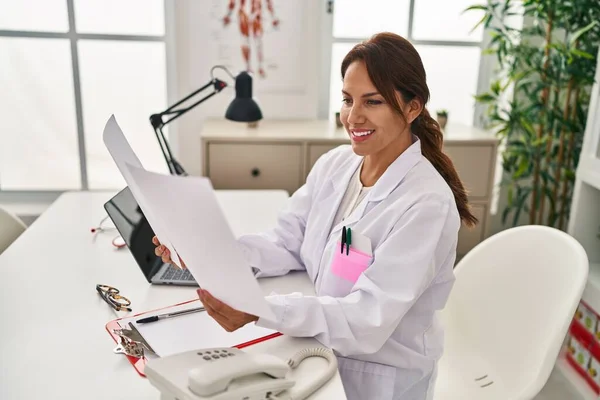 Young Latin Woman Wearing Doctor Uniform Reading Paperwork Clinic — Fotografia de Stock