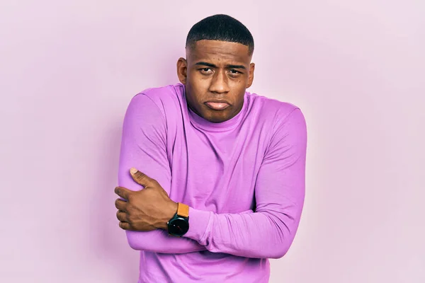 Young black man wearing casual pink sweater shaking and freezing for winter cold with sad and shock expression on face