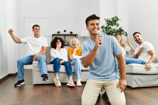 Bir grup genç arkadaş evde mikrofon kullanarak şarkı söylüyor..