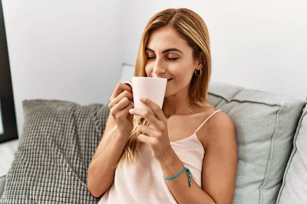 Beyaz kız gülümsüyor. Mutlu bir şekilde evde kahve içiyor..