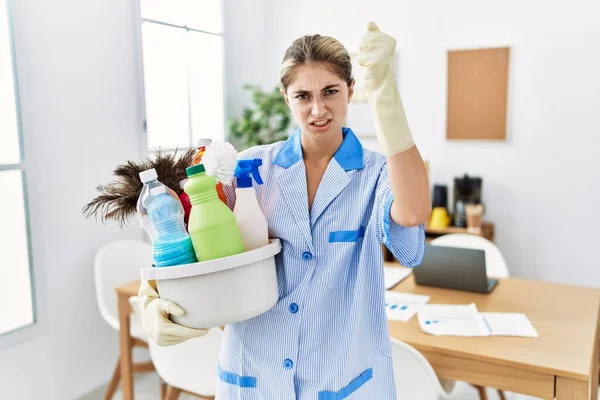 Young Blonde Woman Wearing Cleaner Uniform Holding Cleaning Products Angry —  Fotos de Stock