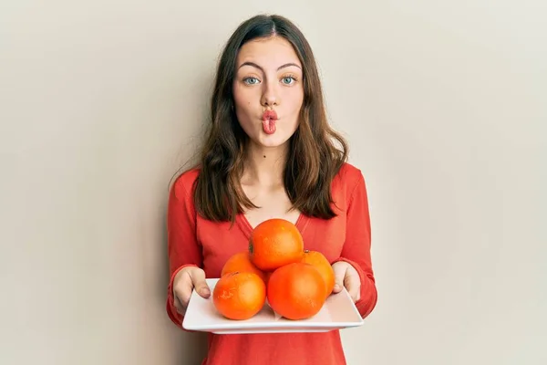 Young Brunette Woman Holding Plate Fresh Oranges Making Fish Face — Stockfoto