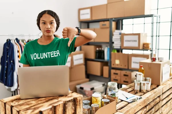 Gönüllü tişört giyen güzel İspanyol kadın kızgın yüzlü dizüstü bilgisayarla çalışıyor, olumsuz işaret baş parmakları aşağıda, reddedilme konsepti ise reddedilmiş. 