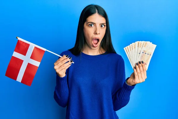 Mladá Hispánka Držící Denmarkovou Vlajku Korunové Bankovky Vyděšená Šokovaná Překvapením — Stock fotografie