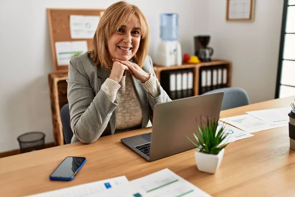 Middle age businesswoman smiling happy working at the office.