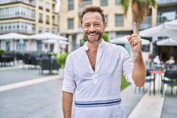 Şehirdeki orta yaşlı adam bir numaralı parmağını gösterip onu işaret ederken kendinden emin ve mutlu bir şekilde gülümsüyor.. 