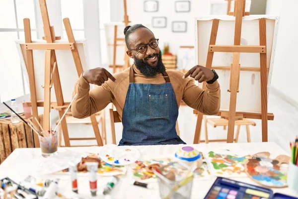 Sanat stüdyosundaki Afrikalı Amerikalı sanatçı, kendine güveni tam görünüyor, kendini gururlu ve mutlu bir şekilde gösteriyor.. 