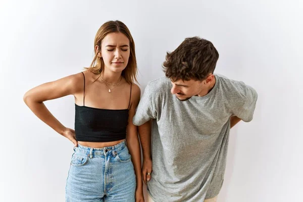 年轻漂亮的夫妇一起站在孤立的背痛的背景音乐上 用手触摸背 肌肉酸痛 — 图库照片