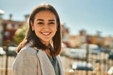 Genç İspanyol kız gülümseyerek şehirde mutlu mesut dikiliyor..