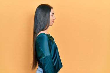 Mavi gözlü güzel bir kadın zarif bir gömlek giyiyor. Yan tarafa bakıyor, rahat bir poz veriyor. Kendine güvenen bir gülümsemesi var.. 