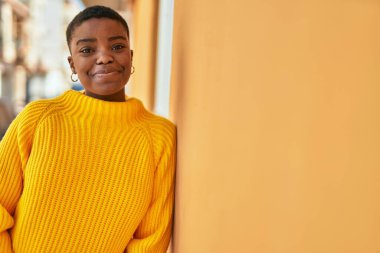 Genç Afrikalı Amerikalı kadın gülümseyerek şehirde mutlu mesut duruyor..