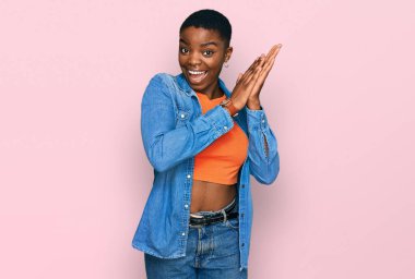 Genç Afrikalı Amerikalı kadın, günlük giysiler giyip alkışlıyor, mutlu ve neşeli alkışlıyor, gururla gülümsüyor. 