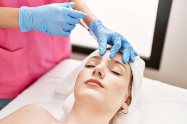 Klinikteki yaşlanma karşıtı tedavi için kadın yüzüne botoks yapan doktor..