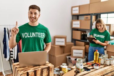 Bağışta gönüllü tişört giyen genç adam ve kadın bir fikir ya da soruyla şaşırmış durumda. 