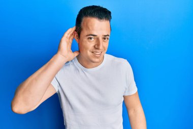 Sıradan beyaz tişörtler giyen yakışıklı genç adam. Kulağı kulağında gülümseyen ve dedikoduları ve dedikoduları dinleyen. Sağırlık kavramı. 