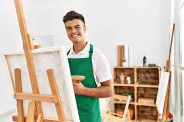 Genç İspanyol adam resim stüdyosunda kendine güvenen gülümsüyor.