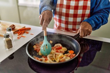 Mutfakta kıdemli adam yemek pişiriyor.
