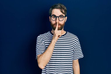 Sakallı, çizgili tişört ve gözlüklü beyaz bir adam sessiz olmak istiyor. sessizlik ve gizli konsept. 