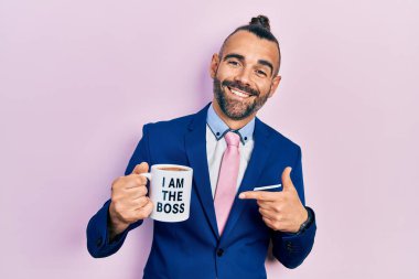 Genç İspanyol adam, patron kahve fincanından içiyor. Gülümsüyor, mutlu bir şekilde elini ve parmağını gösteriyor. 