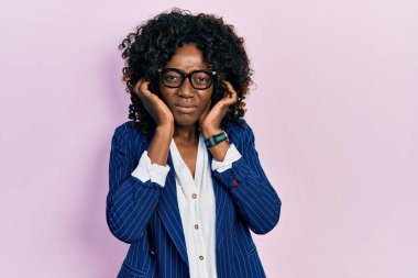 Genç Afro-Amerikalı kadın, iş kıyafetleri ve gözlük takıyor. Yüksek sesli müzik sesi için kulakları parmaklarıyla kapatıyor. sağır kavramı. 