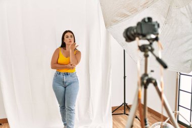 Fotoğrafçılık stüdyosunda model olarak poz veren genç ve güzel bir İspanyol kadın kameraya bakıp havada bir öpücük savuruyor ve sevimli ve seksi oluyor. aşk ifadesi. 