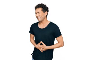 Genç, yakışıklı bir adam, elleri karnında, gündelik siyah tişört giyiyor çünkü mide bulantısı, acı verici bir hastalık kendini iyi hissetmiyor. Ağrı kavramı. 