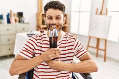Genç Arap, resim stüdyosunda tekerlekli sandalyede fırça tutan engelli bir sanatçı..