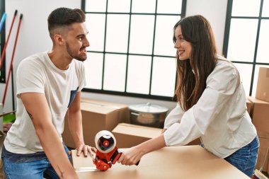 Genç İspanyol çift mutlu bir şekilde gülümsüyor. Yeni evlerinde karton kutu paketliyorlar..