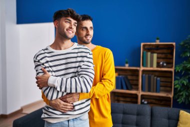 İki erkek, evde birbirlerine sarılıyorlar.