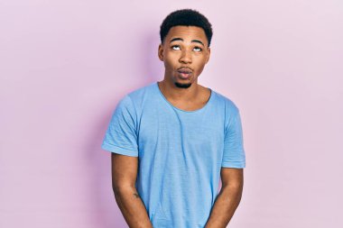 Gündelik mavi tişört giyen genç Afro-Amerikan adam dudaklı balık suratı yapıyor, çılgınca ve komik bir jest. Komik ifade. 