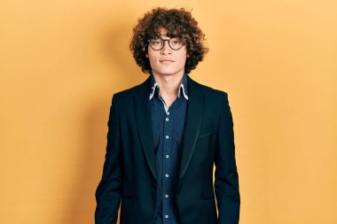 İş ceketi giyen yakışıklı bir genç ve yüzünde ciddi bir ifade olan gözlüklü. Basit ve doğal bir şekilde kameraya bakıyorsun.. 