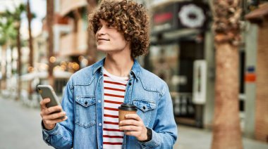 Genç İspanyol adam şehirde akıllı telefon kullanıyor.