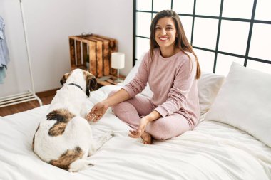 Yatakta köpekle oynarken kendine güvenen genç bir kadın.