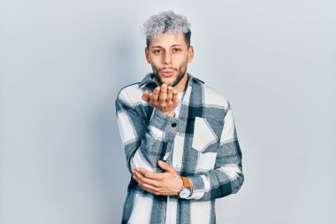 Modern boyalı saçlı, gündelik tişörtlü genç İspanyol bir adam kameraya bakıyor ve havada bir öpücük savuruyor. Güzel ve seksi. aşk ifadesi. 