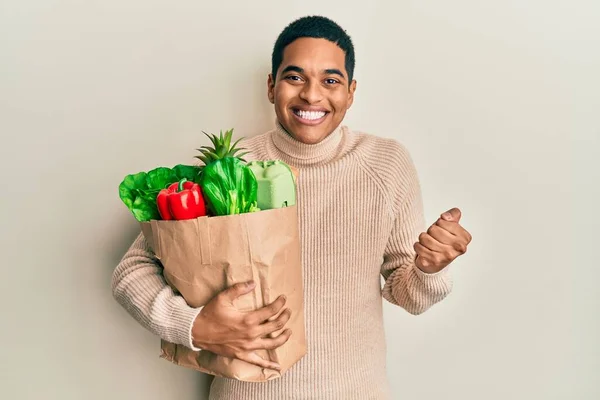 Young Handsome Hispanic Man Holding Paper Bag Groceries Screaming Proud —  Fotos de Stock