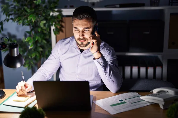 Genç İspanyol iş adamı. Akıllı telefonla konuşuyor. Ofiste fazla mesai yapıyor.