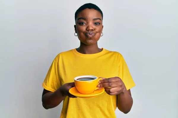 年轻的非洲裔美国女人 脸上带着滑稽的表情 手里拿着咖啡喘气的脸颊 嘴被空气吹胀 — 图库照片